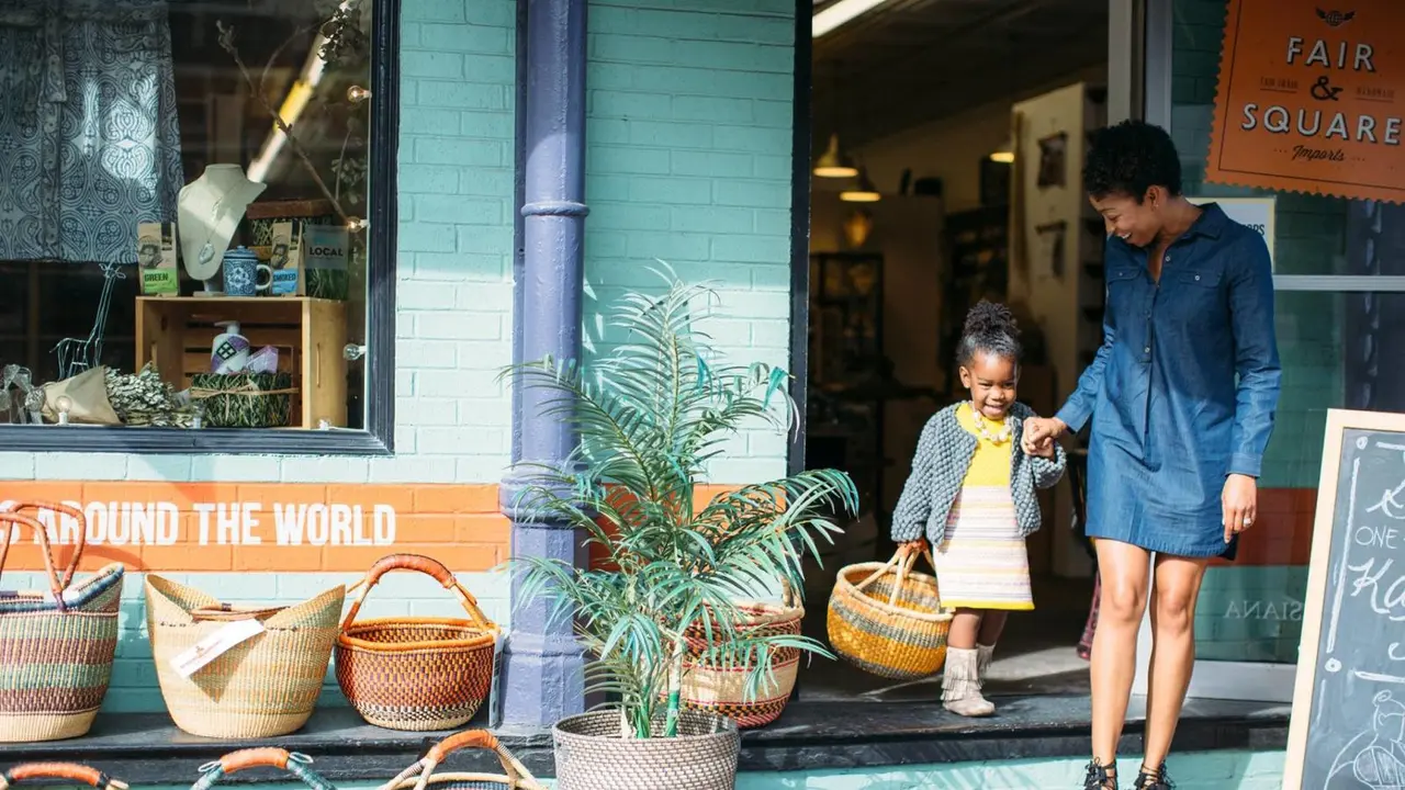 Mother and daughter leaving a teal storefront with shopping bags