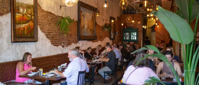 The dining room at Fontina: rows of tables, exposed brick, and guests at dinner
