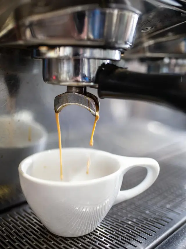 white coffee mug under a machine with coffee dripping into it
