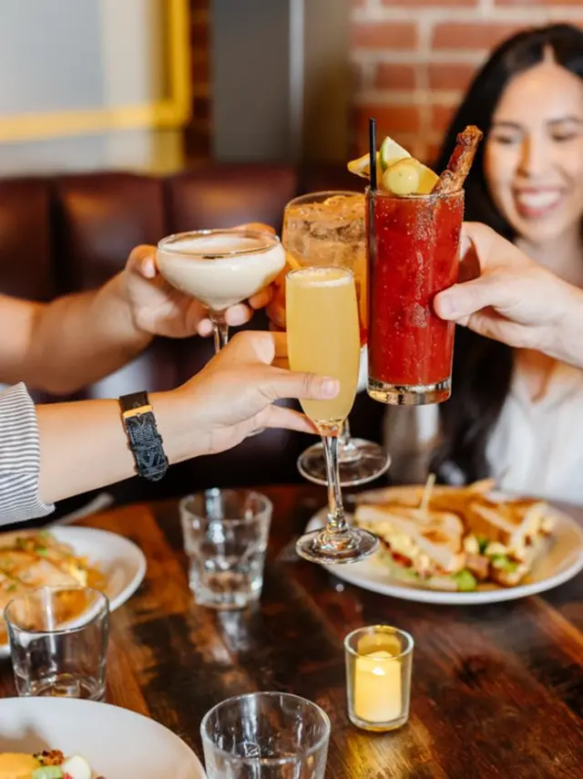 Sugarbacon - people at a table of food, toasting with Cocktails