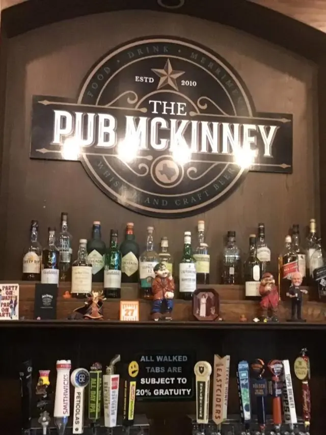 The Pub sign behind beer bottles and taps