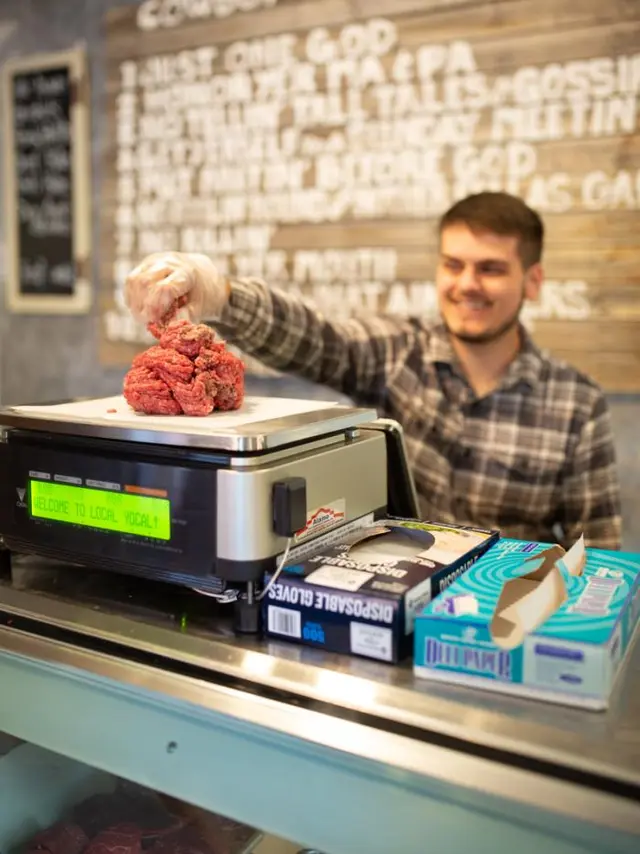 young man measuring ground beef on scale