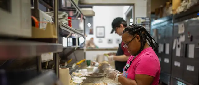 young man and woman in commercial kitchen making sandwiches