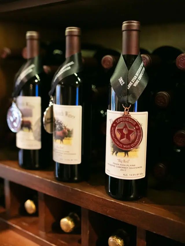 three wine bottles sitting on a shelf