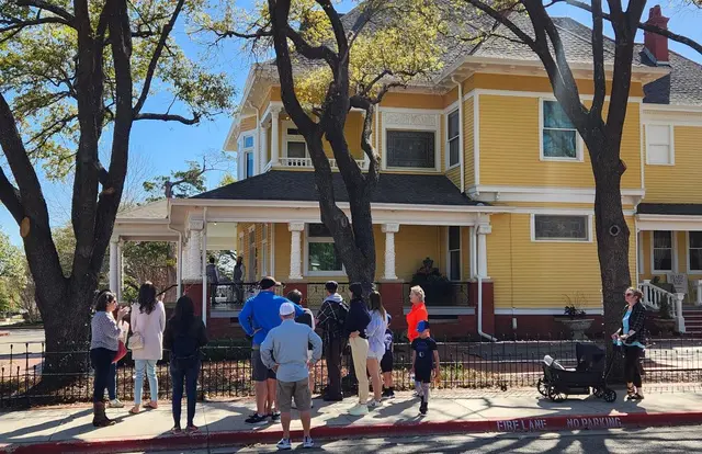 Historic district walking tour - people staying in front of a big old yellow home