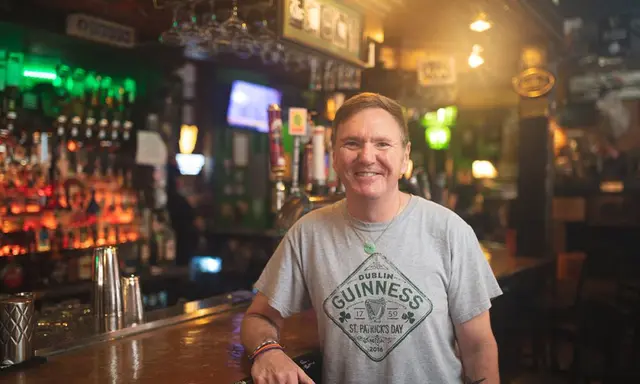 Smiling man wearing a gray Guinness tshirt
