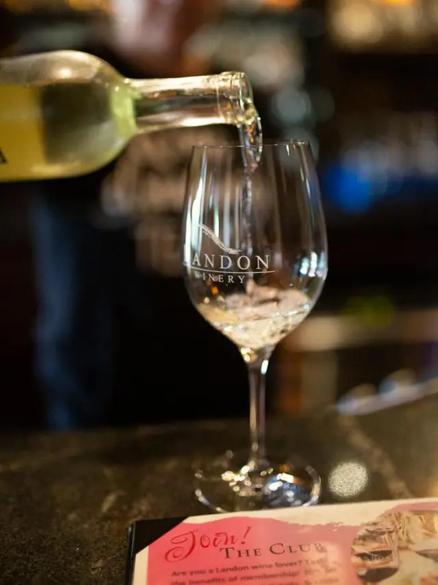 pouring white wine into glass from a bottle