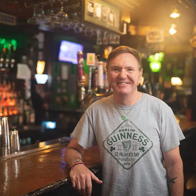 Smiling man wearing a gray Guinness tshirt