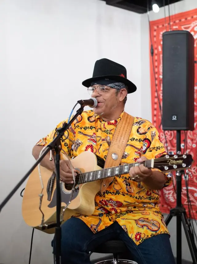 Guitarist wearing a bright yellow shirt and black hat