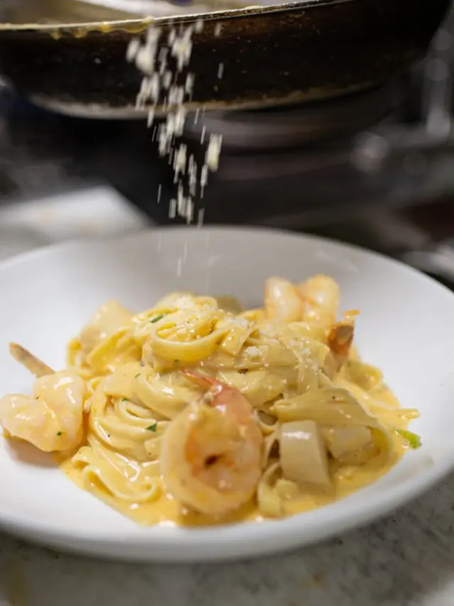 A white plate of linguini with shrimp