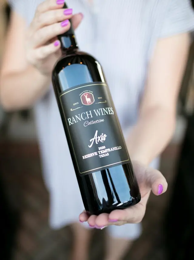 woman's hands holding a wine bottle for the camera