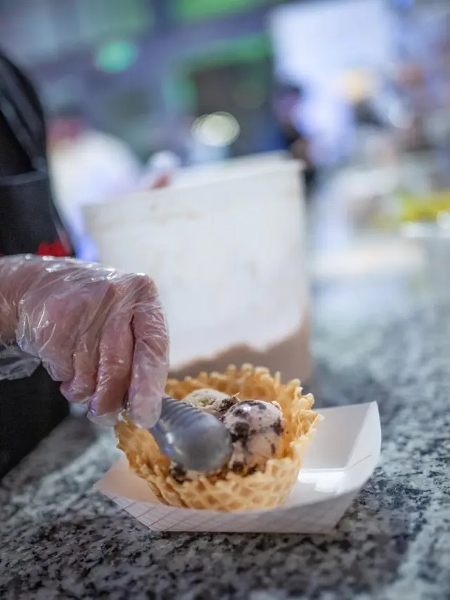 hand Scooping ice cream into a waffle cup